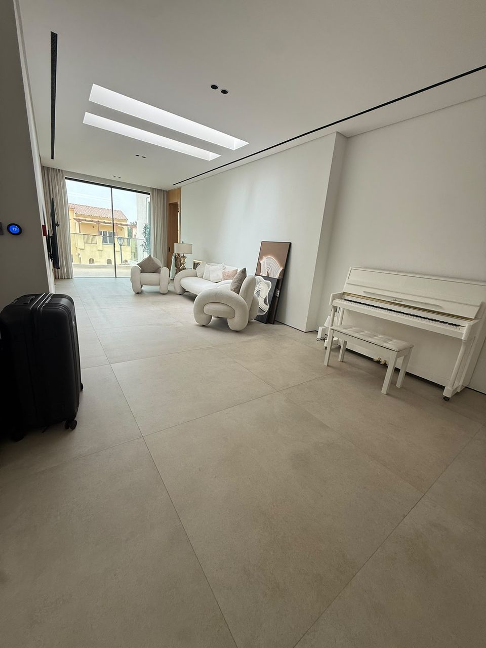 Séjour d'un intérieur contemporain clair équipé de diffuseurs linéaires intégrés au plafond, ouvrant sur un balcon.