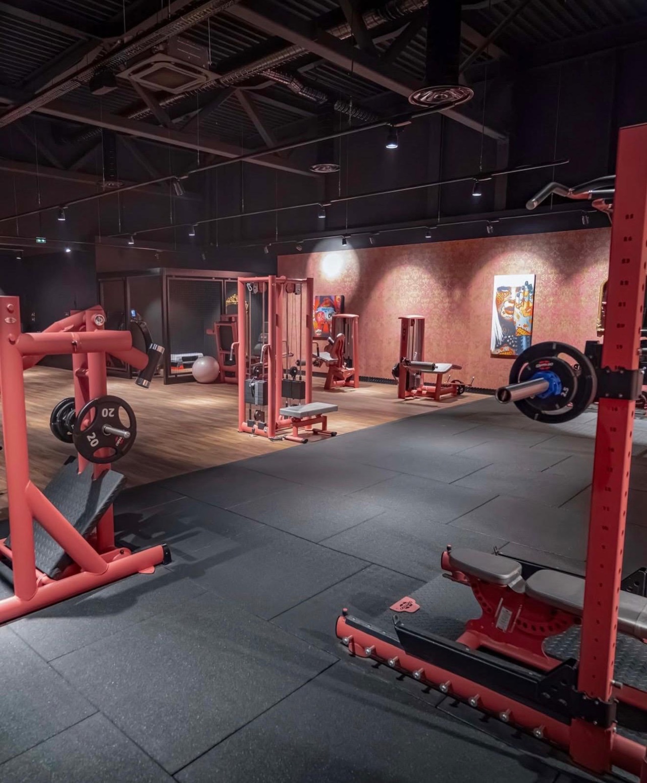 Plateau de musculation d'On Air Fitness à Nanterre : machines et racks rouges, gaines et éclairage apparents en plafond noir.